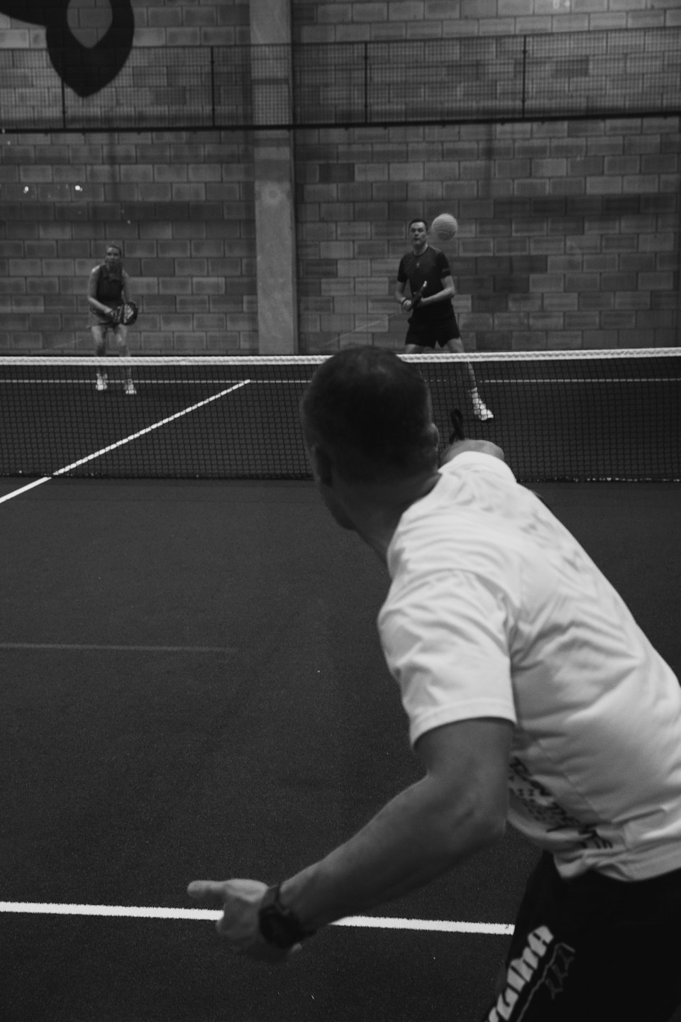 Quattro persone giocano a padel indoor su un campo.
