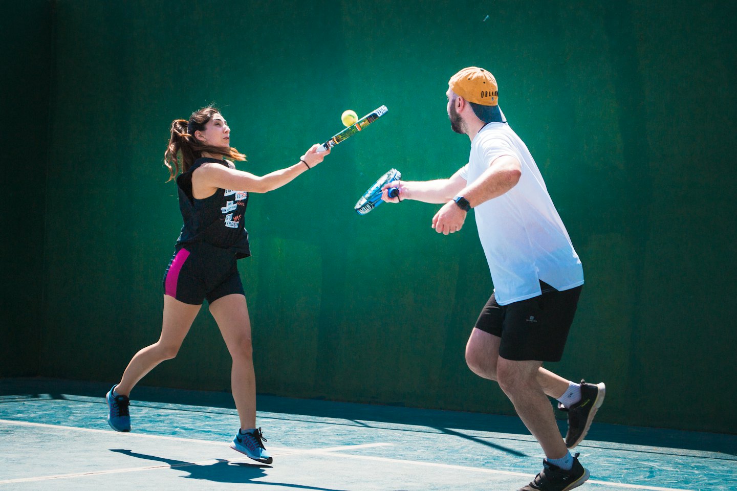 Un uomo e una donna giocano a padel in un campo all'aperto.